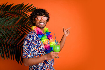 Poster - Photo of man enjoy summer drink cocktail point empty space palm leaves dressed stylish colorful garment isolated on orange color background