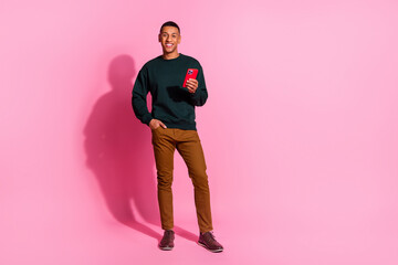 Wall Mural - Full length photo of handsome good mood guy wear sweatshirt texting modern gadget emtpy space isolated pink color background