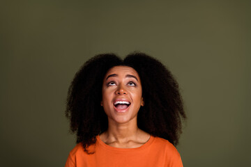 Sticker - Photo of impressed nice woman with perming coiffure dressed orange shirt look up at logo empty space isolated on dark khaki background