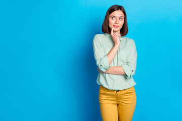 Poster - Photo of minded woman with bob hairstyle dressed teal shirt look at logo empty space finger on chin isolated on blue color background