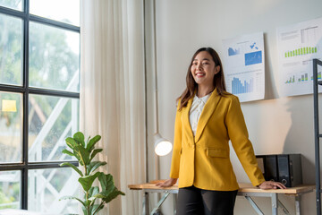 Wall Mural - asian businesswoman smiling leaning on desk in office