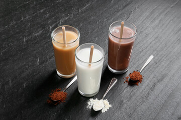 Wall Mural - Delicious protein shakes in glasses and spoons with powder on black table