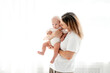 © Any Grant - happy mom with a newborn baby on a white isolated background, space for text, mom hugs and kisses her baby while holding him in her arms, happy motherhood