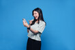 © aratrastudio - Happy Asian young woman using mobile smartphone, read good news online, laugh excited getting offer, great positive surprise, celebrate success on smartphone. Smile girl isolated on blue background