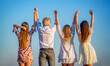 © Yevhen - Young friends holding hands while standing back at camera outdoors. Back view. Company of young girls and guys are standing in the field on a summer day and holding their hands up
