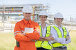 © charnsitr - Petroleum engineers with cross arm pose at oil refinery site