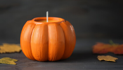 Burning candle in shape of pumpkin on table. Halloween party or thanksgiving day decor