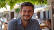 © Vivid Canvas - A handsome Montenegrin man. Montenegro. A cheerful young man sitting at an outdoor cafe, surrounded by greenery, offers a warm and inviting smile. . #motw