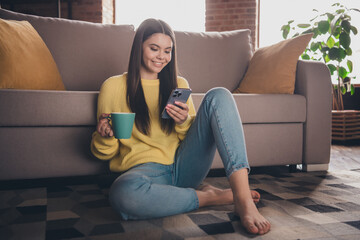 Poster - Full body photo of nice teen girl sit floor couch device drink tea wear yellow clothes modern interior flat indoors