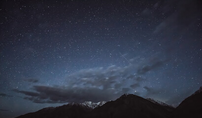 Night landscape in the Tien Shan mountains in Tajikistan in the Pamirs, stars and mountains with snow in the Wakhan Valley