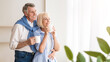 © Prostock-studio - Happy senior couple drinking tea near window and embracing, free space
