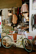 © AnnaStills - Scene depicting vintage bicycle and variety of clothing in store having sale sign. Clothing racks and accessories are visible in background enhancing cozy shop atmosphere