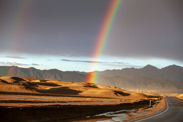 View from highway of double rainbow and dark clouds after cloudburst approaching Death Valley, California