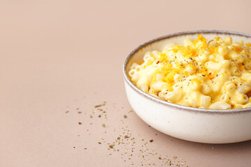 Wall Mural - Bowl of tasty Italian pasta with Cheddar cheese on beige background, closeup