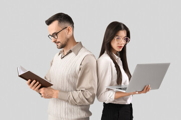 Canvas Print - Young couple in eyeglasses with book and laptop on light background