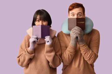 Beautiful young couple with passports and travel pillow on purple background. Winter vacation concept