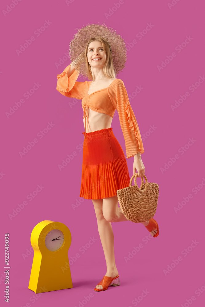 Beautiful young woman with clock on purple background