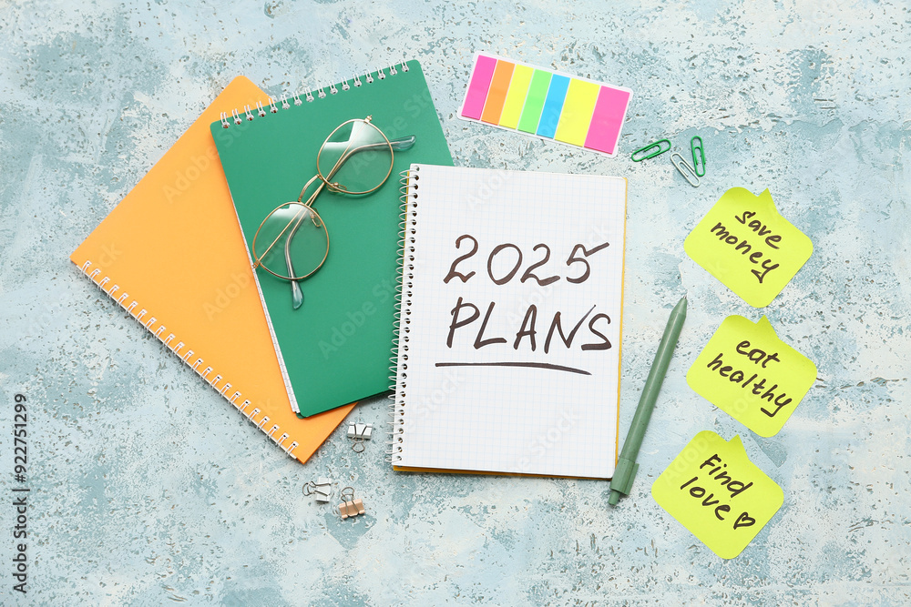Sticky notes with to do plans, stationery and notebooks on blue grunge background. New year goals concept
