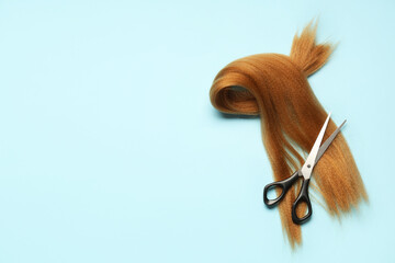 Wall Mural - Red hair strand for donation with scissors on blue background