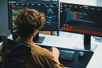 IT developer working online software development on pc monitors at modern home office on coding application screens, creating updated latest program firmware information version concept. Gusher.
