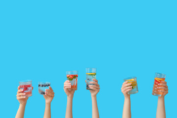 Wall Mural - Many hands with infused water on blue background