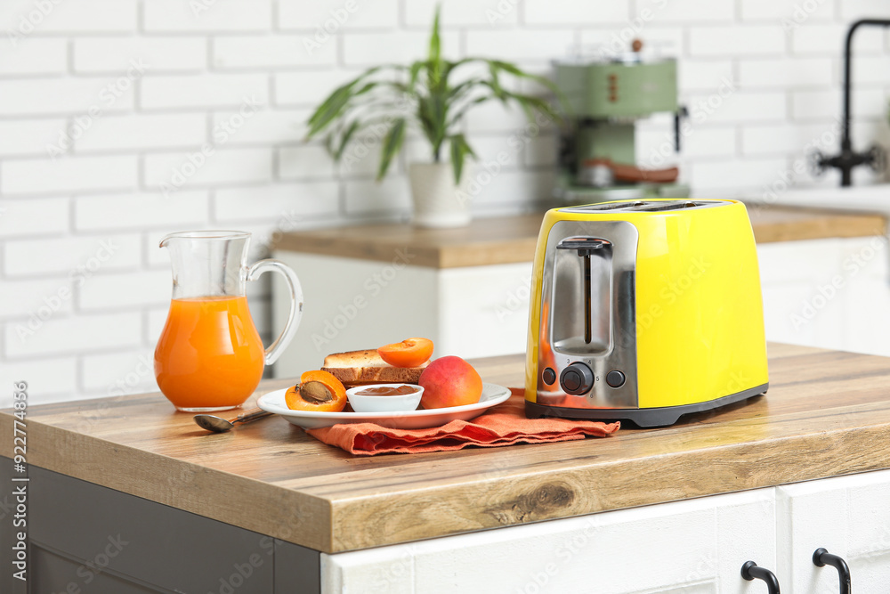 Yellow toaster and plate with bread slices on wooden table in kitchen