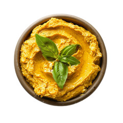 A bowl of yellow hummus with fresh basil leaves