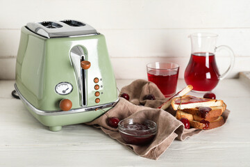 Wall Mural - Green toaster with bread slices and cherries on white wooden background