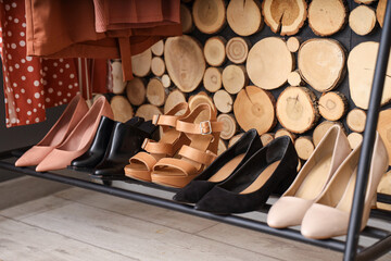 Wall Mural - Stylish female shoes on shelf near wooden wall in room, closeup