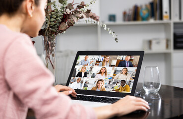 Wall Mural - Young woman working at home on a laptop is holding a video conference discussing important current issues