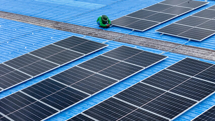 Wall Mural - top aerial of engineer men inspects construction of solar cell panel or photovoltaic cell at roof top. Industrial Renewable energy of green power. factory at urban area. worker working on tower roof.