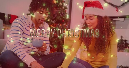 Sticker - Merry Christmas text animation over couple sitting by Christmas tree