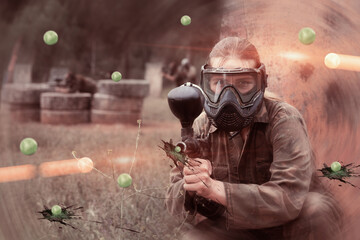 Wall Mural - Portrait of girl paintball player in mask who is aiming in opponents on paintball field