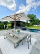 © theplantedwanderer - High-end outdoor living space, a backyard patio with pergola, outdoor rug,  tequila bar, dining set, couch, television, pool with waterfall, umbrella, fire pit and stunning grey patio. Modern vibe.