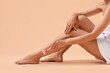 © New Africa - Woman shaving leg on beige background, closeup. Space for text