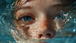 © CHONCHANOK PHOTO - A close-up of a child's face partially submerged in water, showcasing mesmerizing blue eyes and reflections of light on the surface.