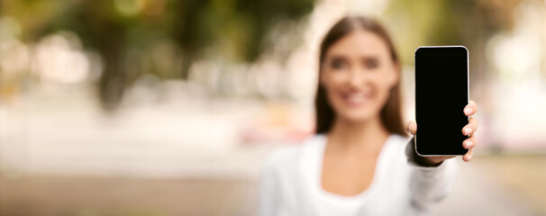 Wall Mural - Unrecognizable Woman Showing Cellphone Empty Screen Recommending Social Helpline Service Or App Standing Outdoor. Shallow Depth, Mockup