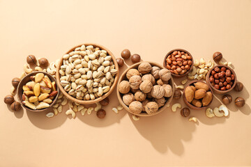 Various nuts in wooden bowls on a beige background