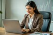 © N7 - A young Indian financial analyst, either a man or woman, working at a desk with financial charts and a laptop.