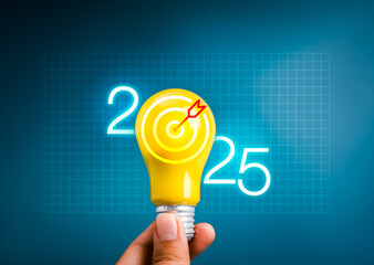 Wall Mural - Happy 2025 New Year with creative idea, technology, business goal, innovation concept. Glow neon 2025 calendar numbers and yellow light bulb with target icon, hold by people's hand, blue background.