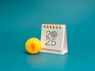 Wall Mural - Happy new year 2025 with innovation technology, creative idea power, business inspiration concept. Minimal 2025 desk calendar standing near yellow ball with lightbulb icon on light blue background.