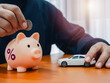 © tete_escape - Car tax, vehicle taxation, refund, monthly debt payments, budget calculate and financial insurance concepts. Percentage icon on piggy bank while person putting coin and white car on wooden table.