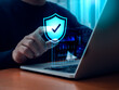 © tete_escape - Cybersecure, worldwide internet network security technology, privacy digital data protection concepts. Safety shield icon hologram pointing by businessman hand while work with laptop computer.