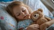 © Oulaphone - Little girl patient lying in hospital bed with mini bear. Children in intensive care.