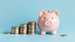 © Cherkasova Alie - Pink piggy bank with stacks of coins on blue background, concept of saving money.