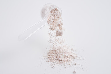 powdered calcium citrate poured from a measured cup. white background isolated high speed freeze mot