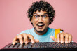 © ViDi Studio - Close up young smart nerd Indian boy IT student wears blue t-shirt casual clothes backpack bag typing on pc computer keyboard isolated on plain pink background. High school university college concept.