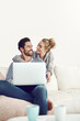 © SunriseDon/peopleimages.com - Happy couple, space or laptop for bonding, choice or movie streaming online on sofa in living room. Home, internet or people relax on social network app, digital website or technology for mockup