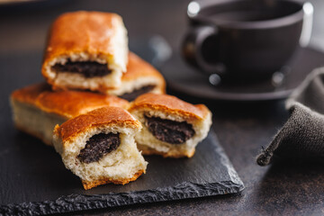 Poster - Sweet bun with poppy seed on black table.