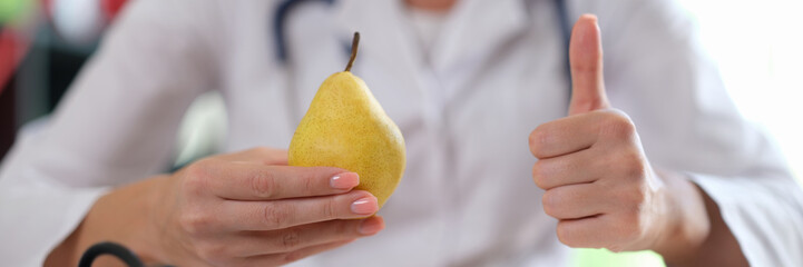 Doctor holding yellow pear and showing thumb-up sign